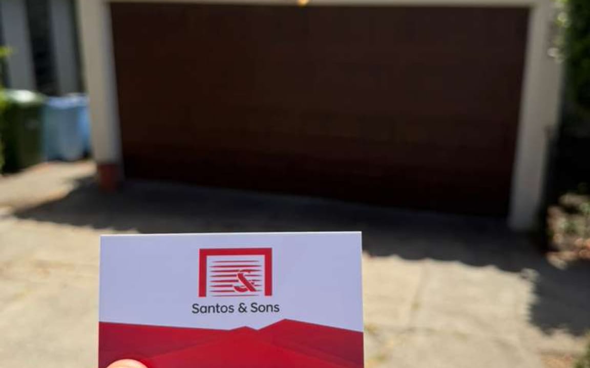 Santos & Sons business card in front of a wood garage door we serviced in Berkeley, CA